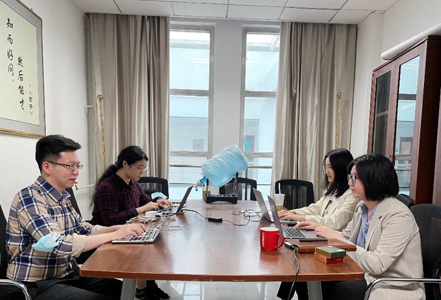 A group of people sitting around a table with laptops Description automatically generated